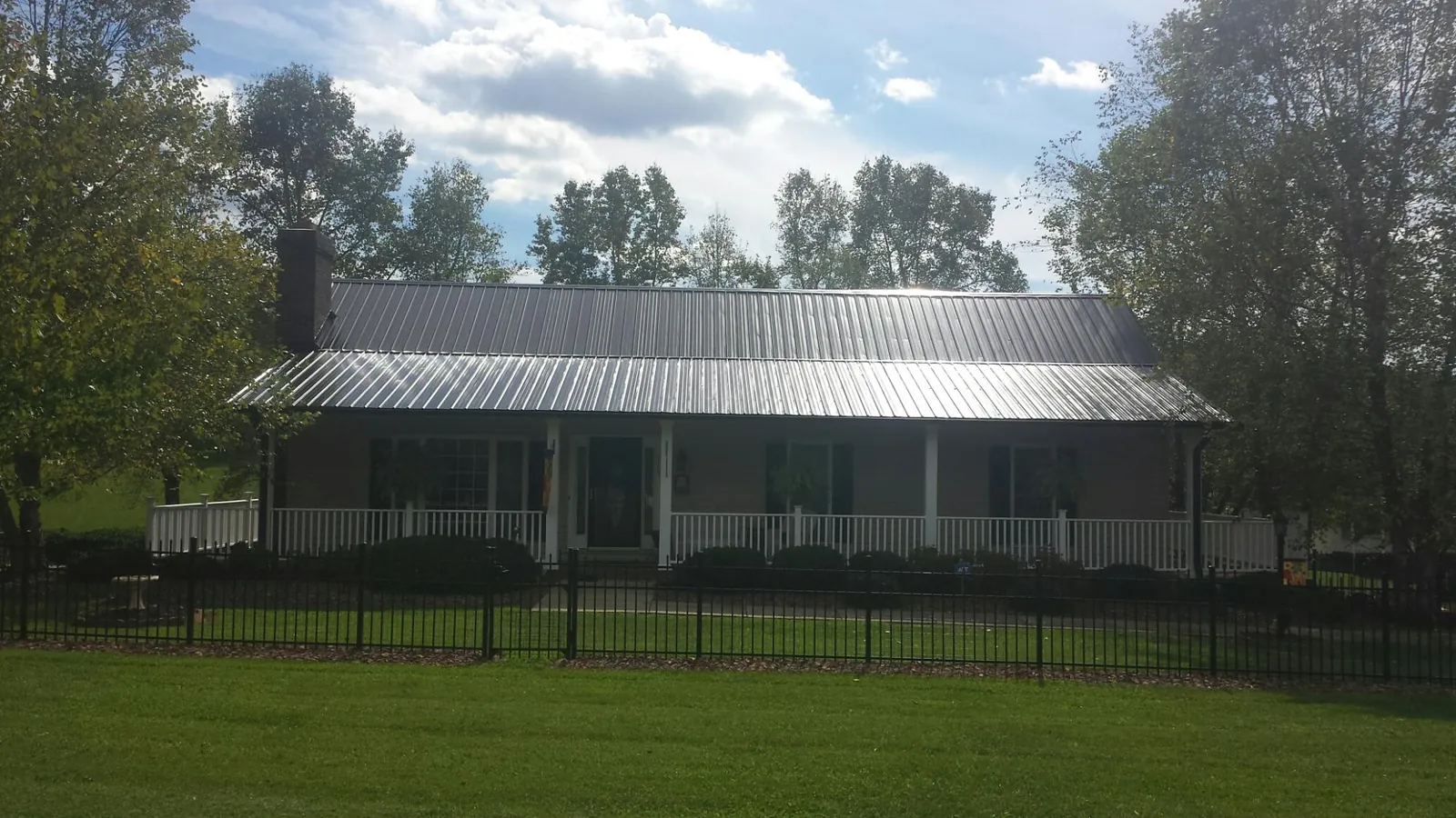 Gray metal roof on a brick ranch with a full width front porch — Gutter Guard Installation work by our crew in Clay City