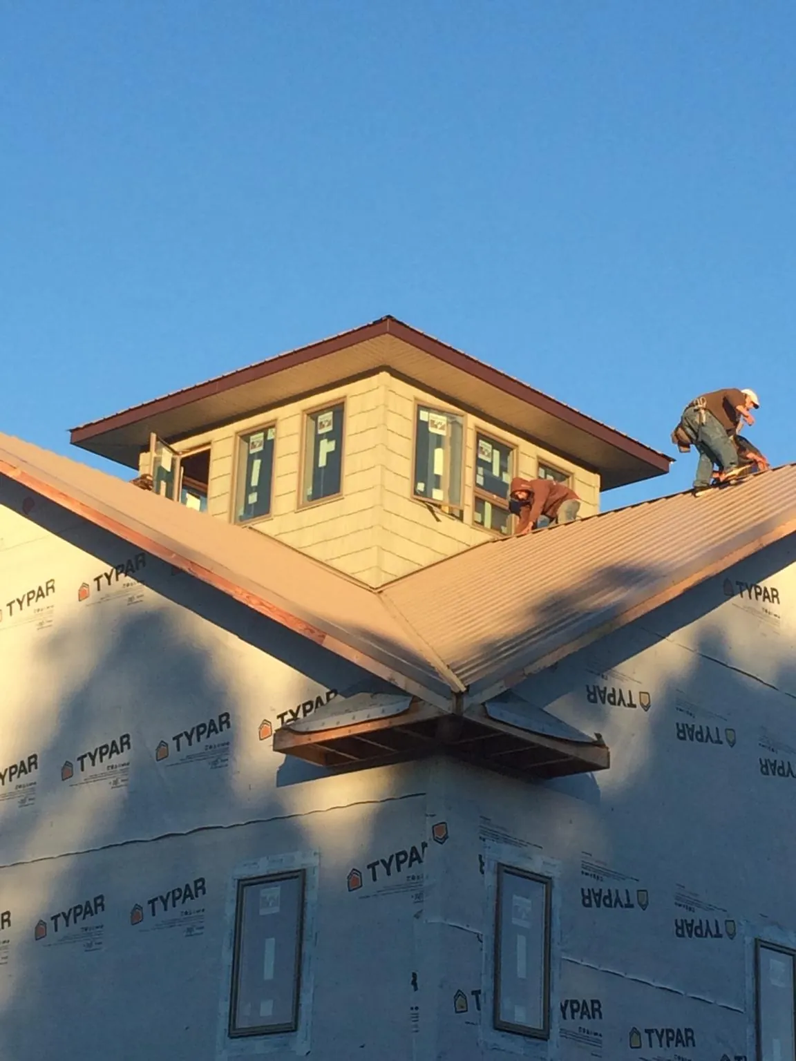 Roofers working around a rooftop cupola on a new metal roof at sunset — Roof Waterproofing in Clay City by Roofing Brothers